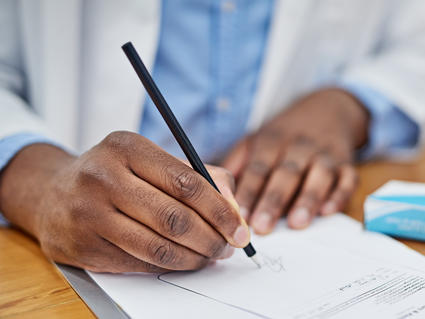 Hands of a doctor as he writes a prescription.