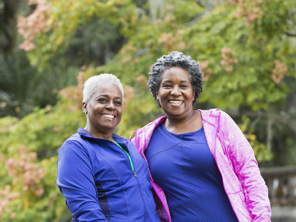 Two women standing together, smiling outside