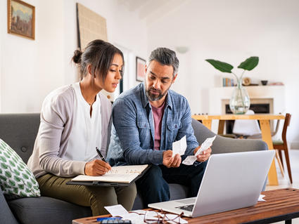 a man and woman looking at a computer and paperwork