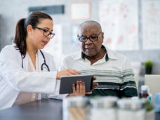 Female doctor showing tablet to senior African-American patient