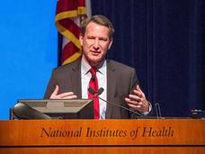 Dr. Norman Sharpless presenting from a podium at a town hall meeting in 2017.