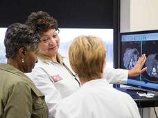 Photo of three women reviewing medical scans in an office. 