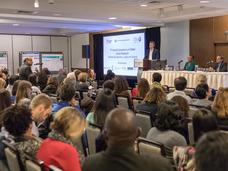 Attendees watching a presentation at the symposium.