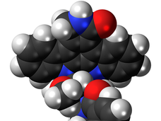 3D molecular model of midostaurin, an FDA-approved drug for treating certain patients with acute myeloid leukemia, showing black carbon atoms, white hydrogen atoms, blue nitrogen atoms, and red oxygen atoms connected in a complex molecular structure.