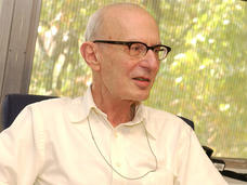 Alan Rabson, M.D. sitting in a desk chair in his office, engaged in a conversation