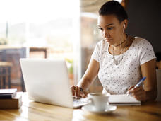 A college-aged Hispanic woman sitting working on her laptop.