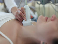 A medical professional performs an ultrasound on a patient's neck to examine the thyroid gland.