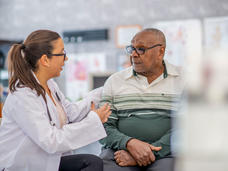 A man and a woman talking in a clinical setting. 