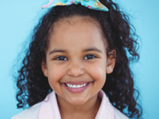 Girl with black curly hair and a bow with a light blue background