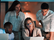 four people examining a laptop