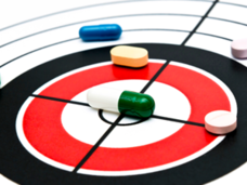 Target shows one medication capsule in the bull’s eye, with four more tablets in the outside rings of the target. Illustrates the difficulty in finding the precise medication for treating diseases like cancer. 