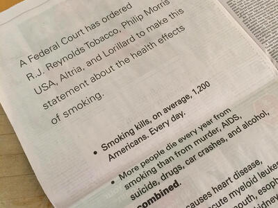 A photo of a newspaper page with text that includes a court ordered statement from major tobacco companies along statistics abou the negative health impacts of smoking.