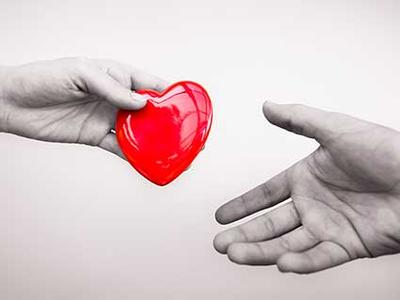 Photo of a hand passing a heart-shaped disc to another person's hand.