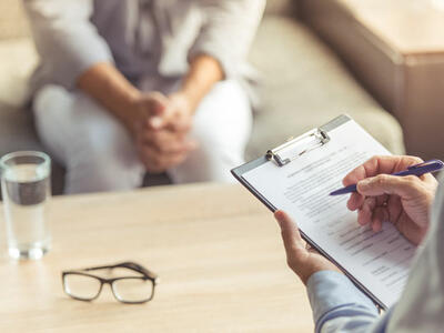 Doctor holding clipboard while interviewing a patient.