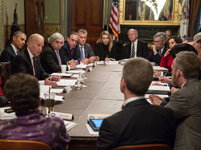 Then-Vice President Biden is sitting at a long rectangluar table in an ornate room addressing a large group of people for the first meeting of the Cancer Moonshot Task Force.