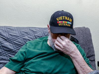 Un veterano de la guerra de Vietnam deprimido con la cabeza gacha mientras se cubre la cara con la mano