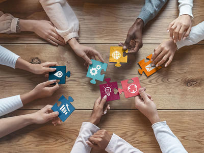 Seven hands hold puzzle pieces