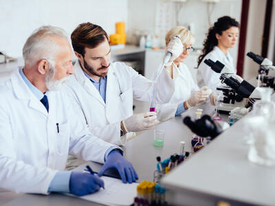 Mixed age range team of scientists in research laboratory conducting science experiments.