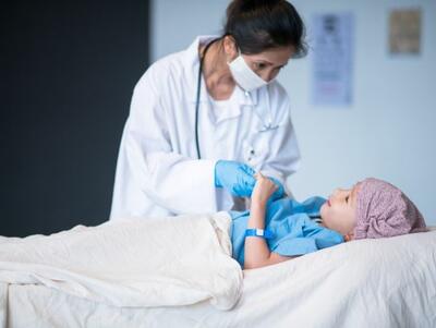 Un médico habla con un niño acostado en una cama de hospital.