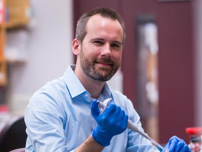 Photo of Dr. Kevin Janes in his laboratory holding a pipet