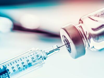 A syringe withdrawing liquid from a glass vial