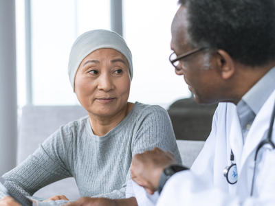 Photo of a woman in head covering sitting and meeting with her doctor.