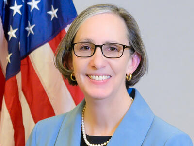 NCI Director Dr. Rathmell stands in front of the U.S. flag