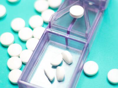 An image of white pills in a gray, plastic pill cutter