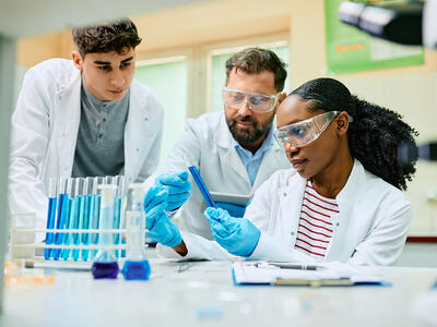 Group of scientists examining liquid sample in test tube during scientific research in laboratory