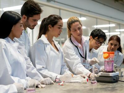 An image of a female researcher in the lab with several students to her left and right.