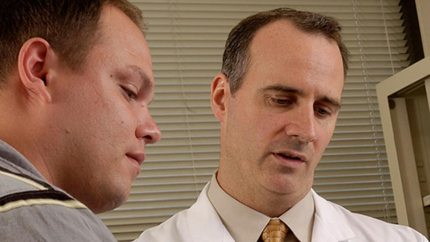 Doctor explaining information to a young male patient who is listening carefully.