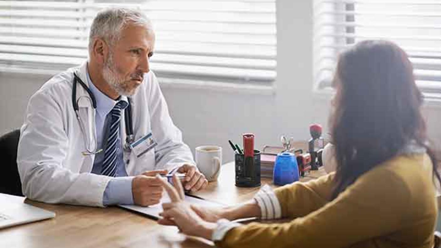 Seated male doctor conversing with seated female patient