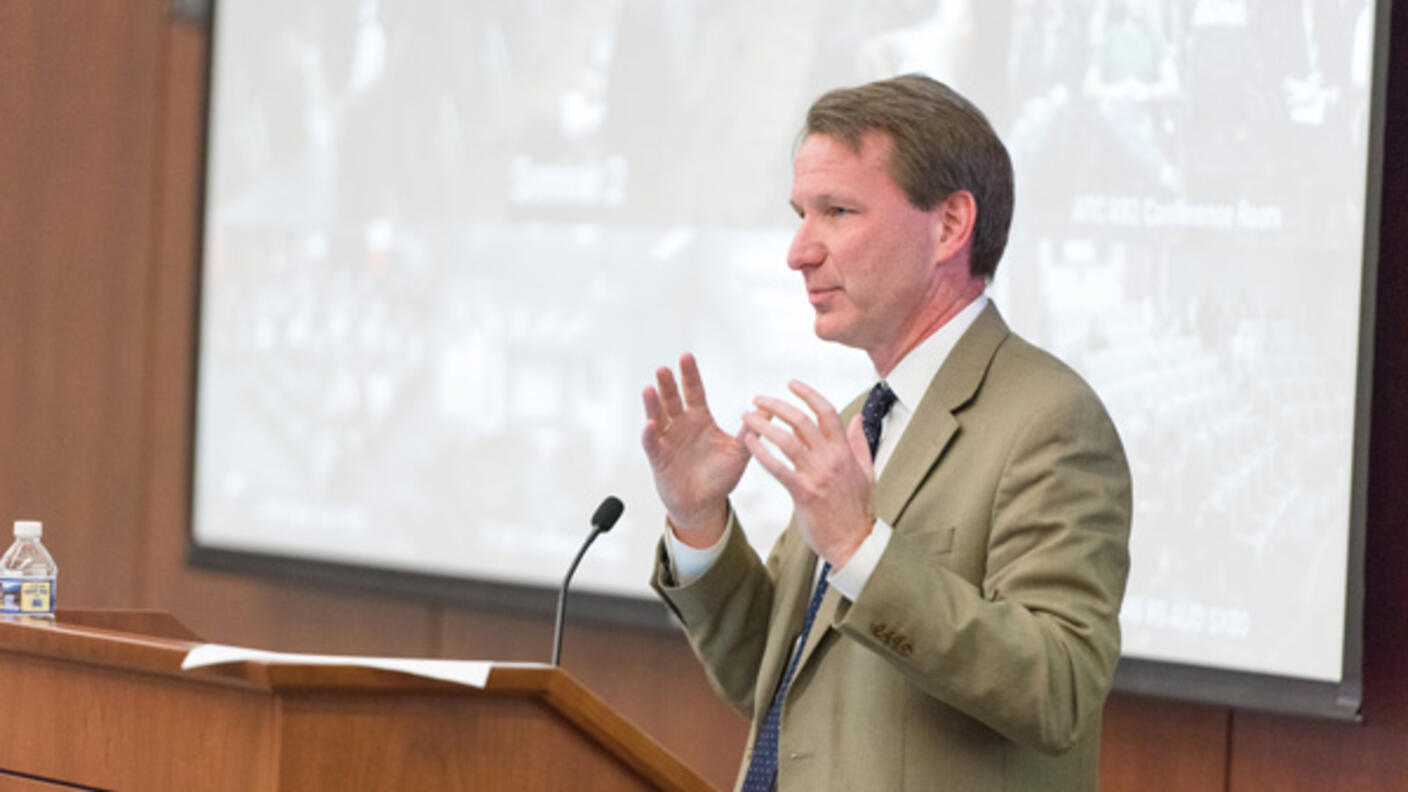 Dr. Norman E. Sharpless speaking at a podium.