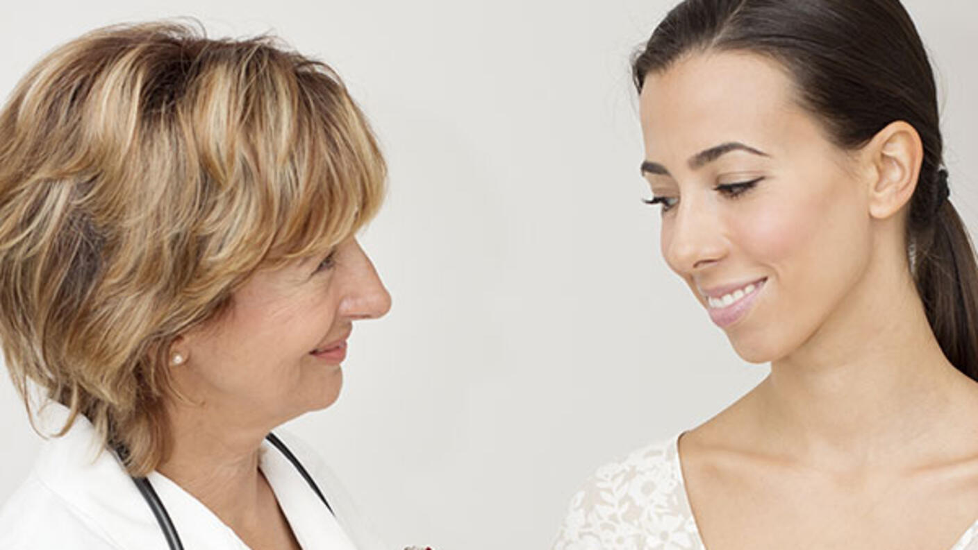 Female doctor talking with an appreciative, young female cancer patient.
