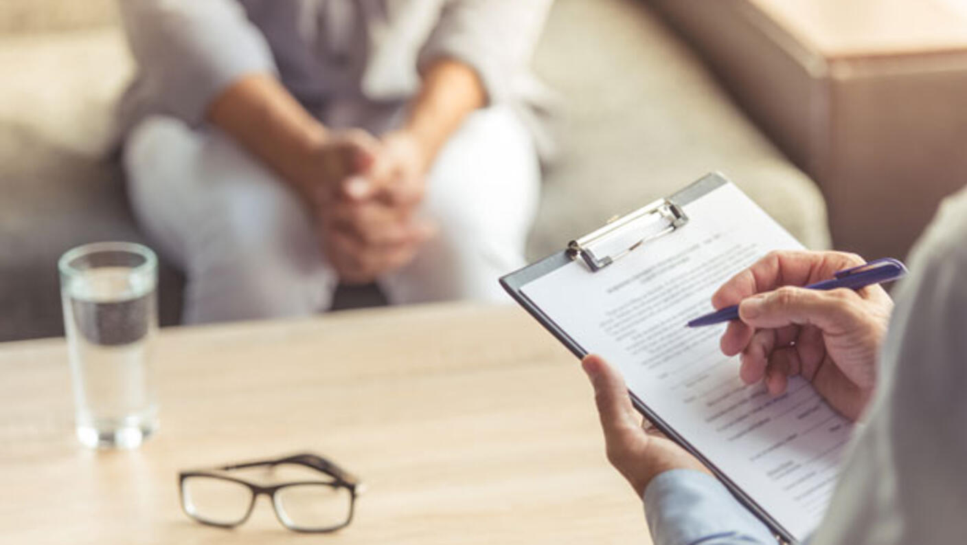 Doctor holding clipboard while interviewing a patient.