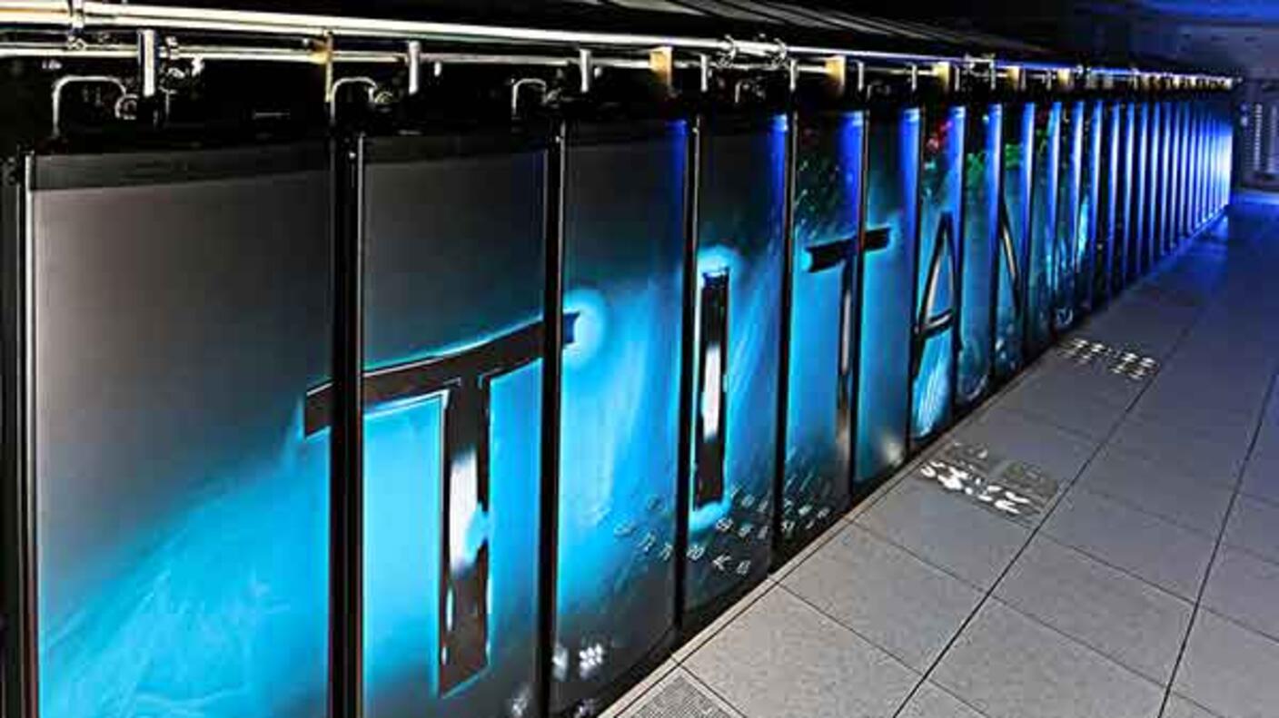A row of grey Metallica structures connected by metal at the top. The word “TITAN” runs across the front of the metal structures and a bluish glow emits from the background. The floor is made of grey tile.