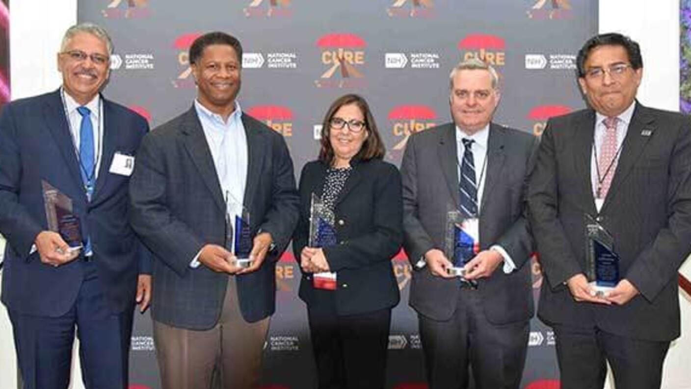 Five CURE scholars standing together, each holding an award for lifetime achievement.