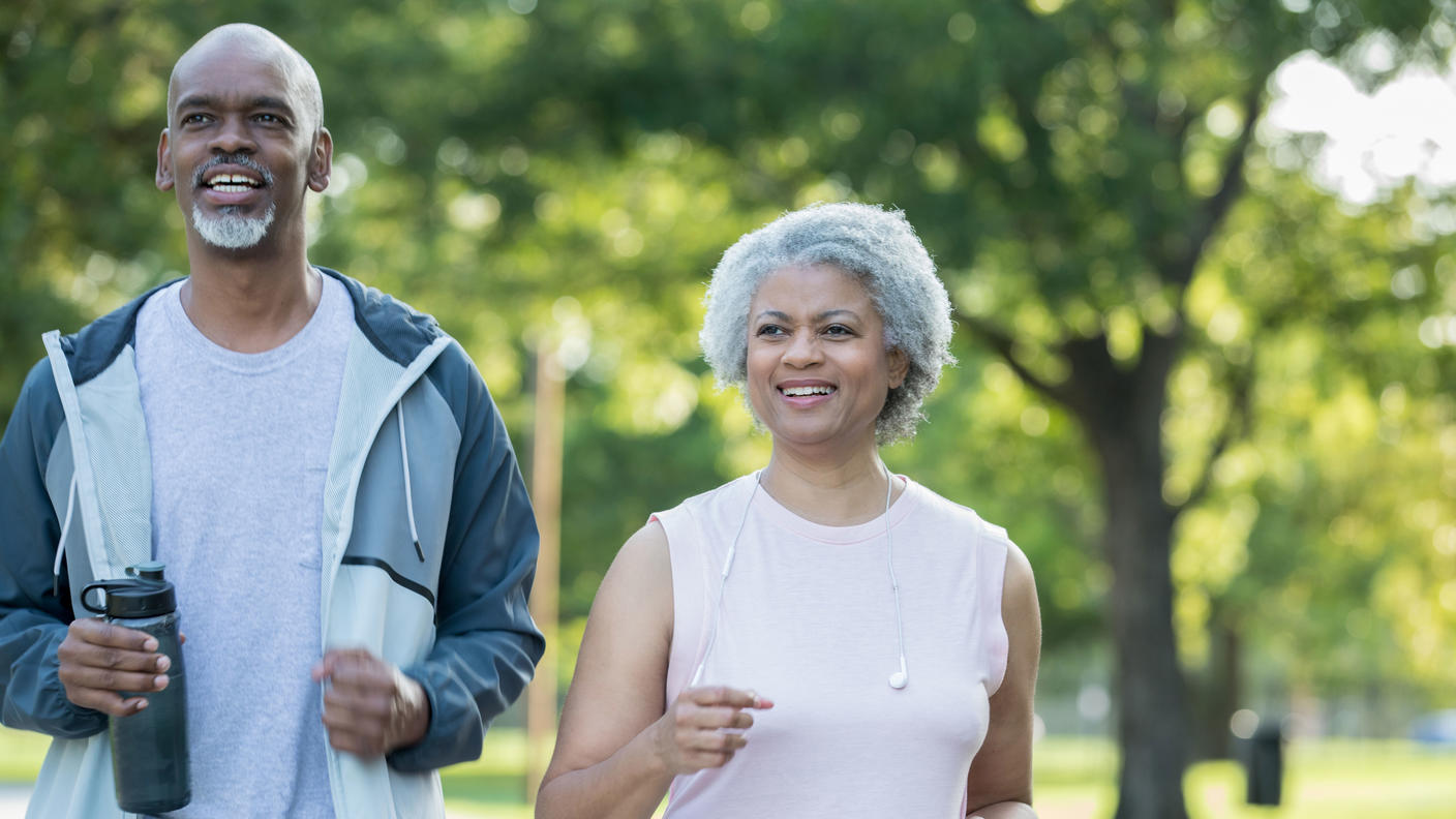 An older African American couple walking in a park.