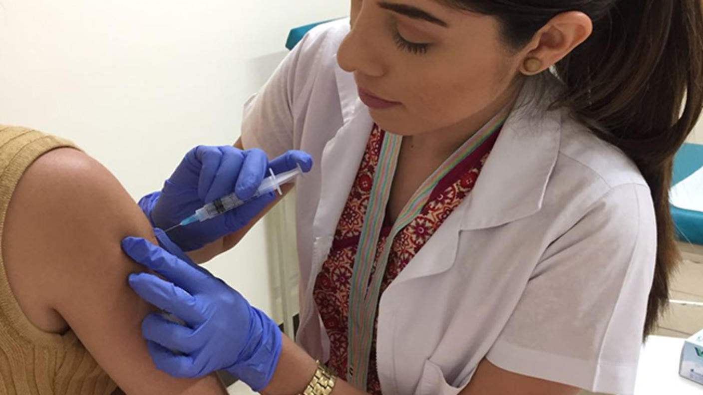A nurse administering an HPV vaccine to a young woman.