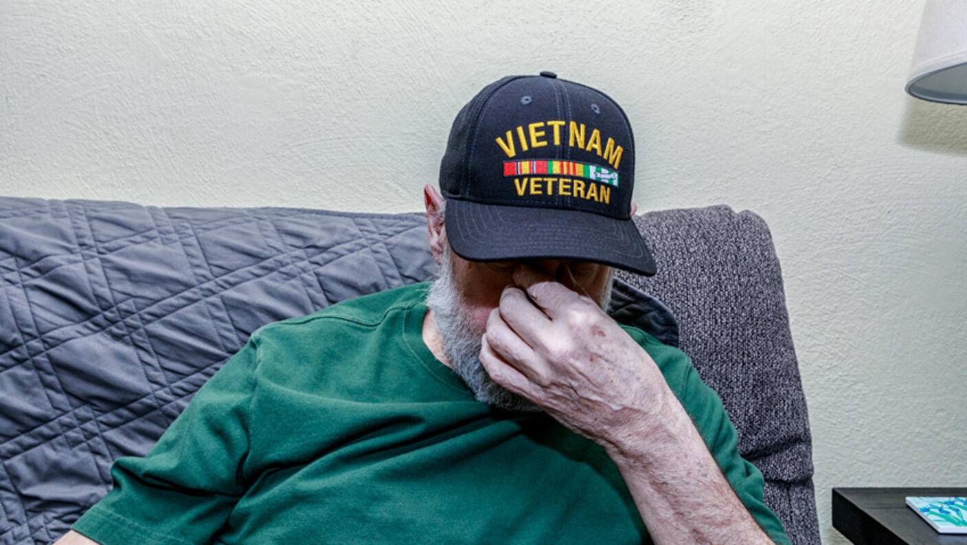 A depressed Vietnam War USA military veteran has his head down while covering his face with his hand