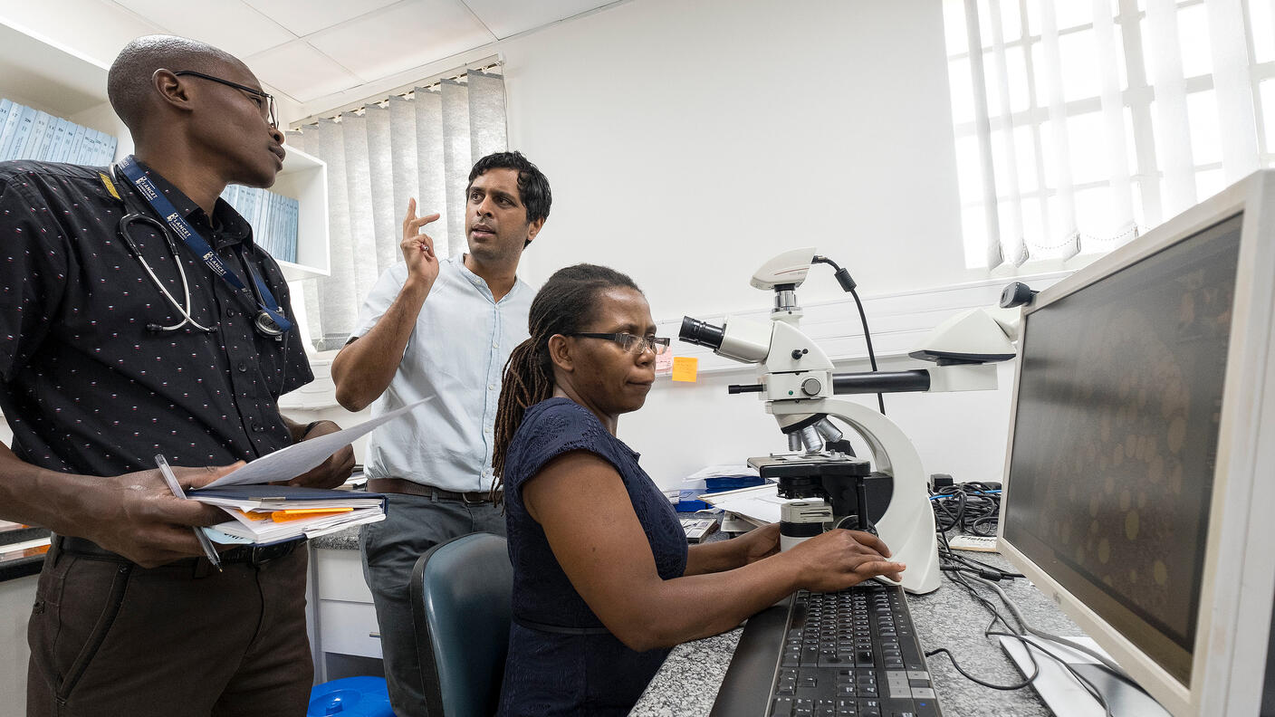 Dr. Satish Gopal in discussions with two office staff during his previous job in Malawi in Sub-Saharan Africa.