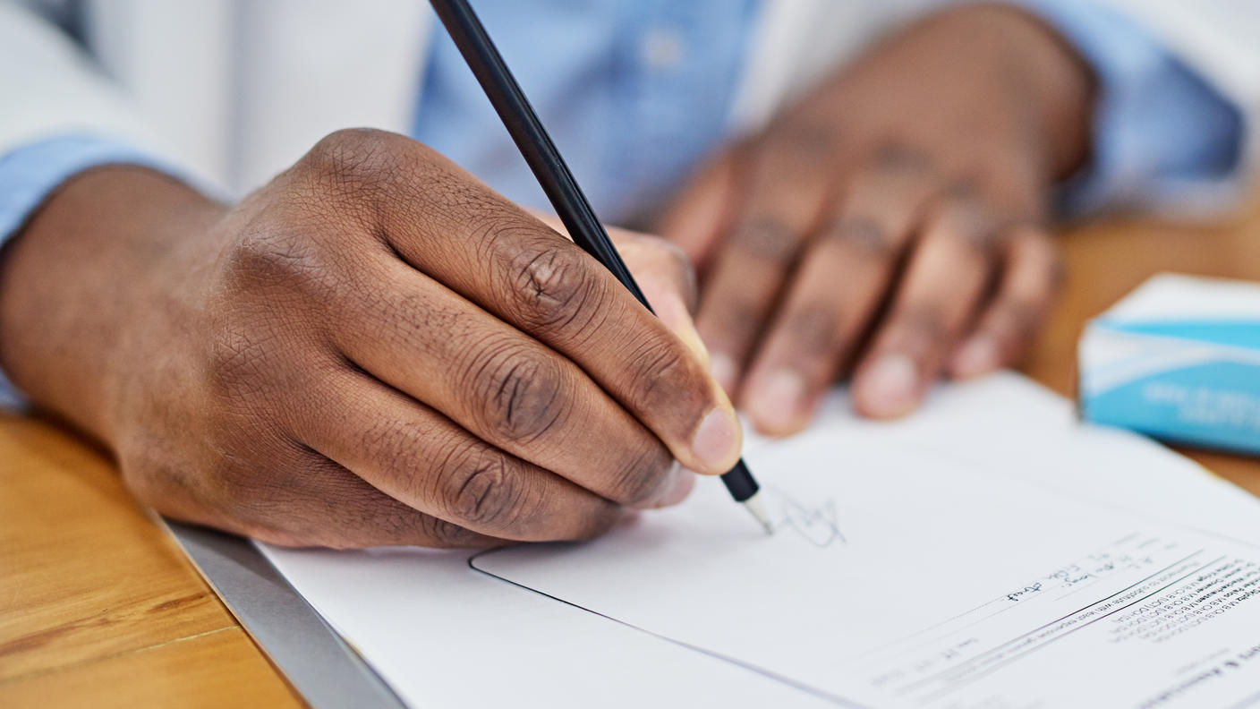Hands of a doctor as he writes a prescription.
