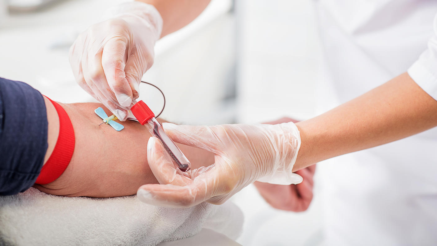 An image of a blood being collected into a tube from a male patient.