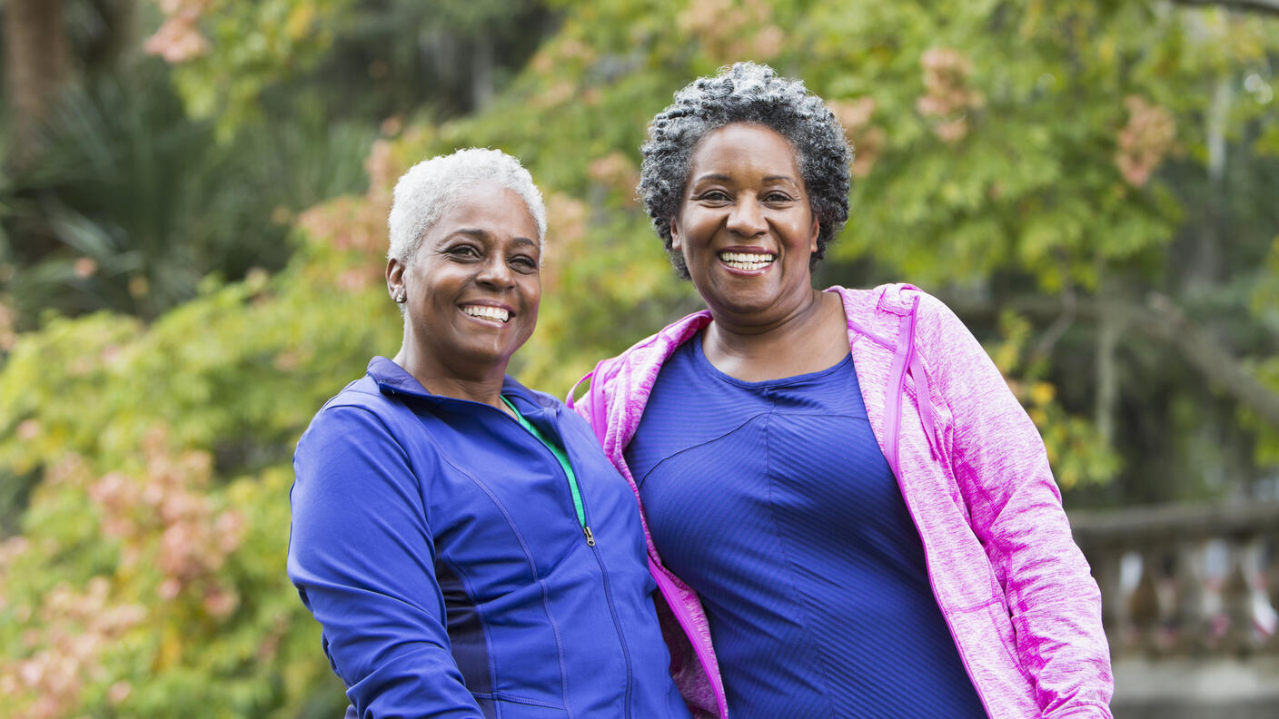 Two women standing together, smiling outside