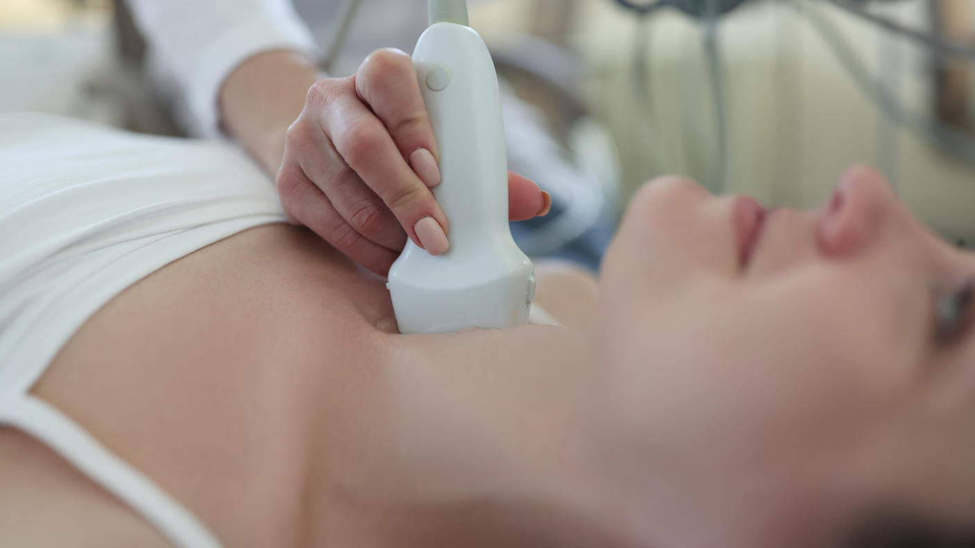 A medical professional performs an ultrasound on a patient's neck to examine the thyroid gland.
