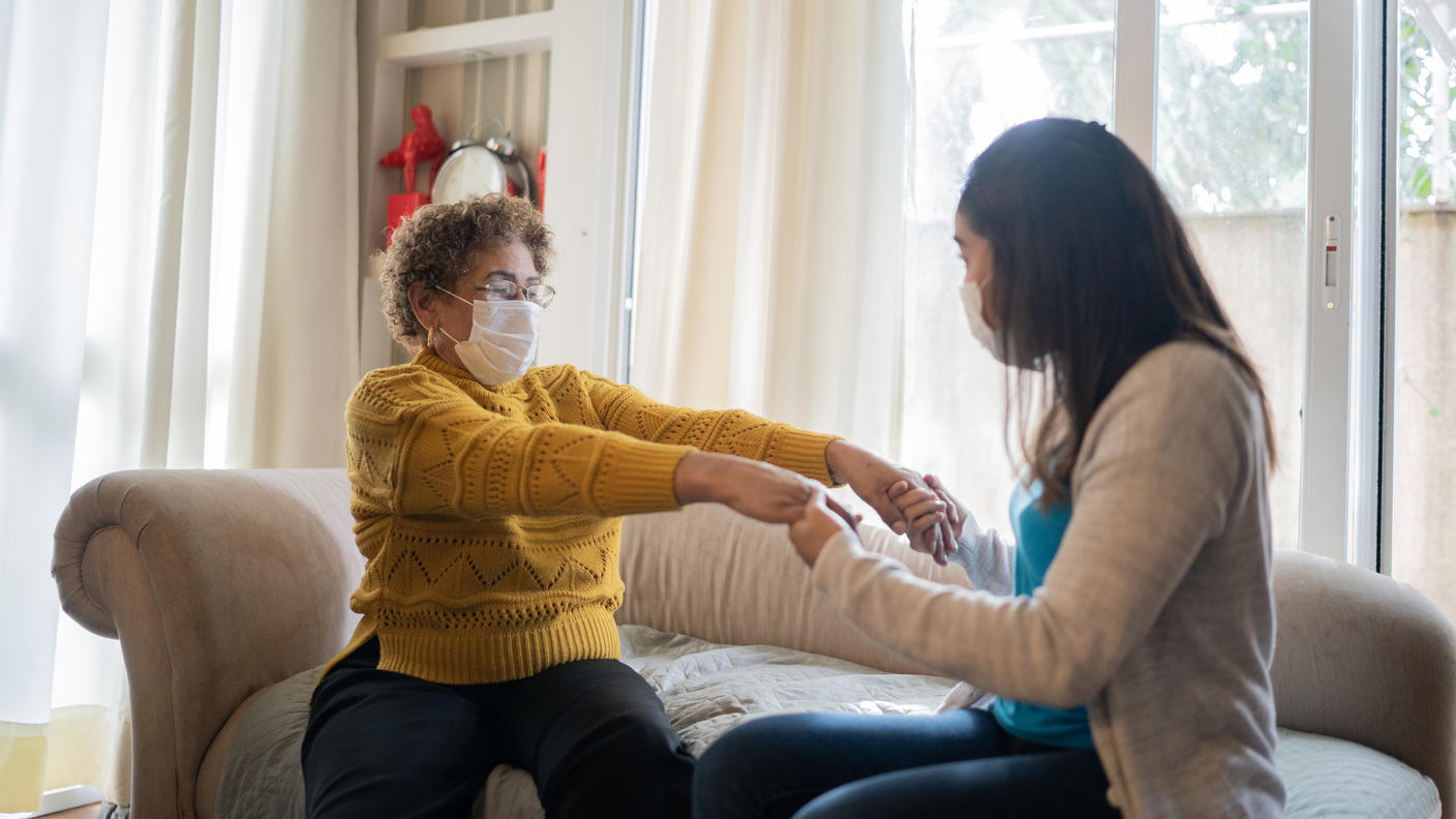 Una promotora de salud haciedo ayudando a una paciente a estirar sus brazos