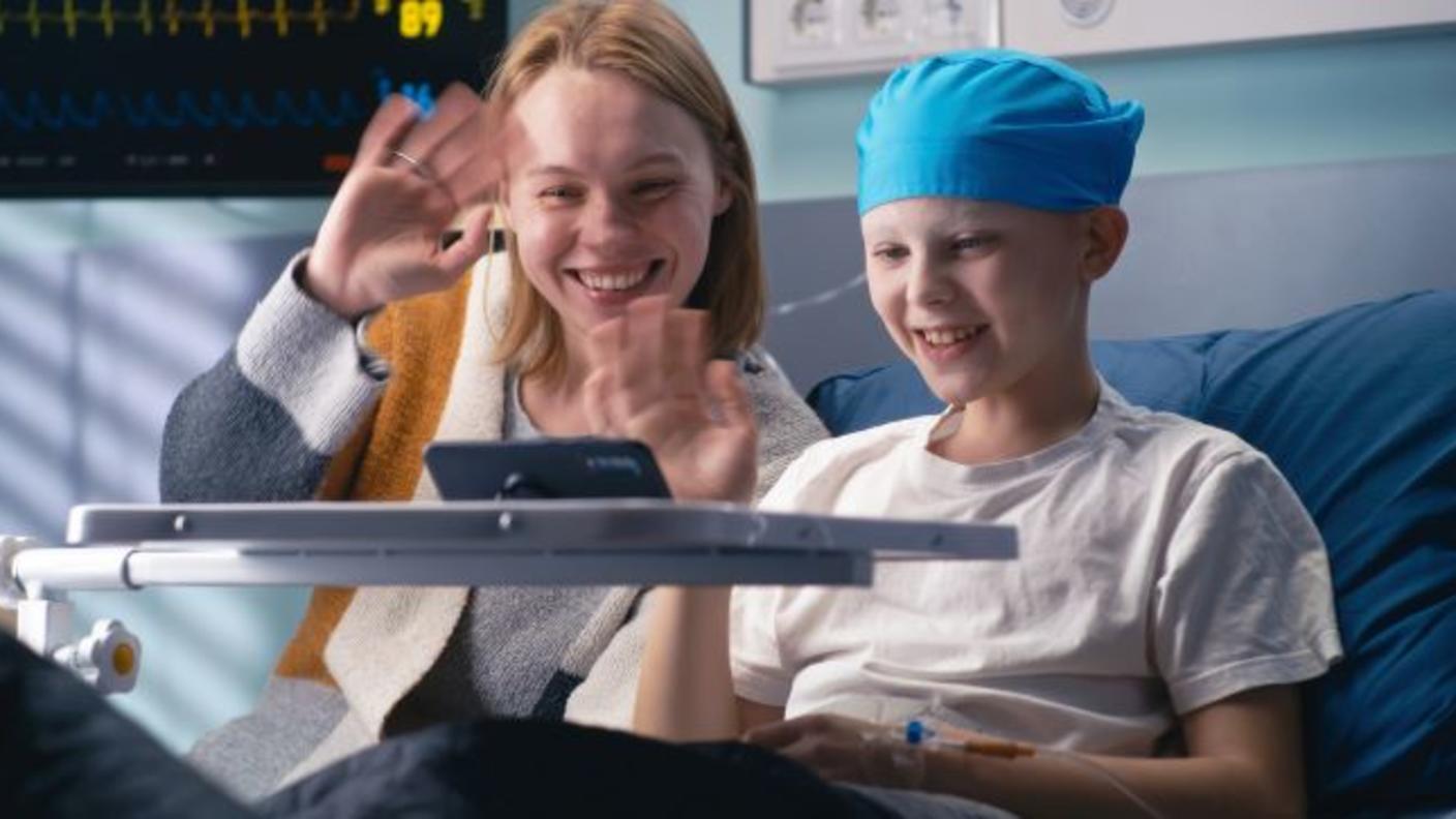 A child with cancer and his mother talking with family via a tablet computer.