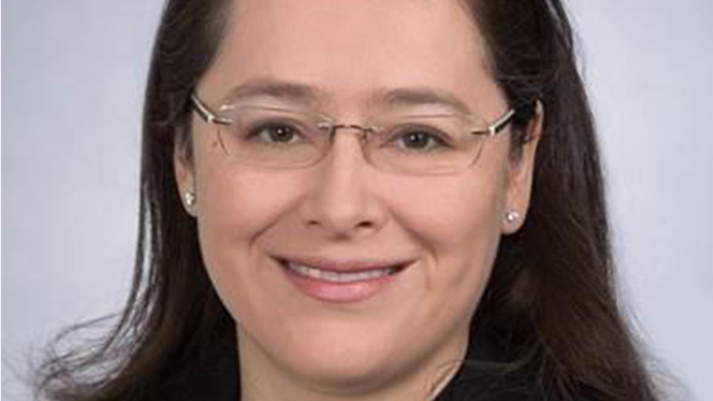 A professional headshot of Dr. Paula Aristizabal, a Latina with a light skin tone, dark hair, and glasses, smiling at the camera.