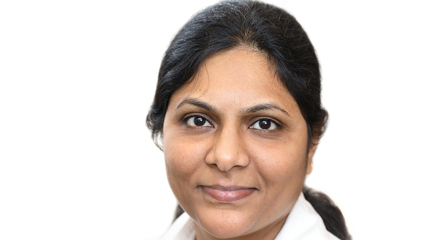 Headshot of Indian woman (Dr. Subhashini Jagu) with hair tied back in a ponytail, wearing a white shirt in front of a white background.