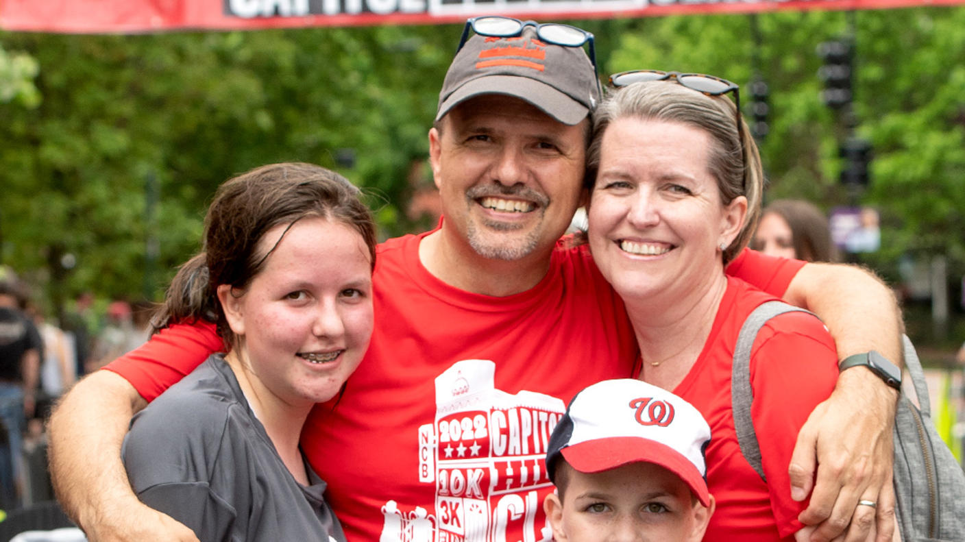 Jason Levine standing with his wife, daughter, and son at the finish line of a race.
